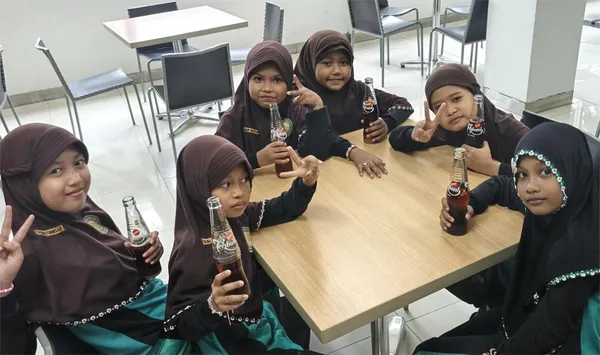 Siswa menikmati produk minuman gratis sebagai bagian dari fasilitas kunjungan pabrik Sosro